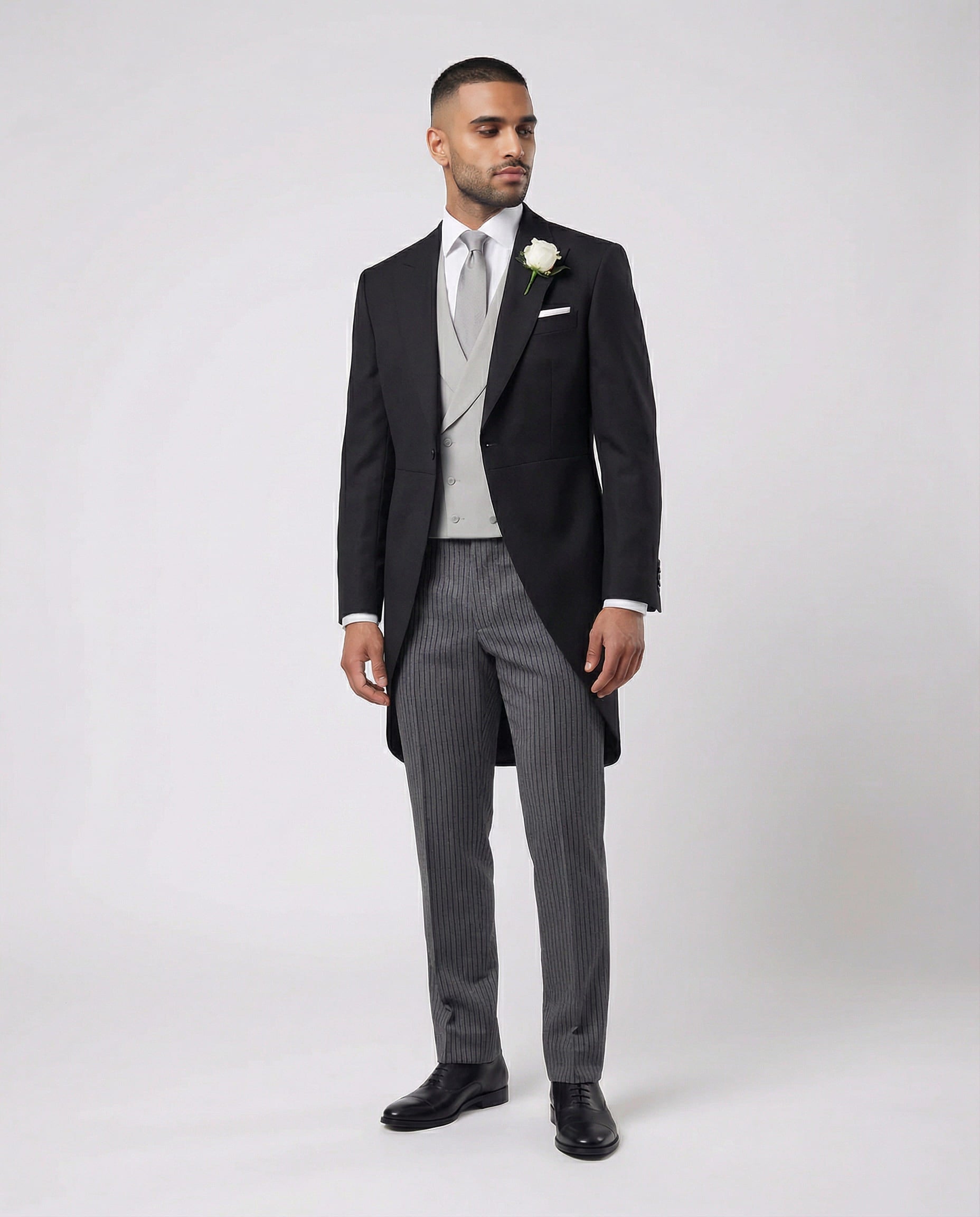 Mann im anthraziten Cutaway mit hellgrauer Weste und Stresemann Hose seitlich gezeigt mit offenem Knopf