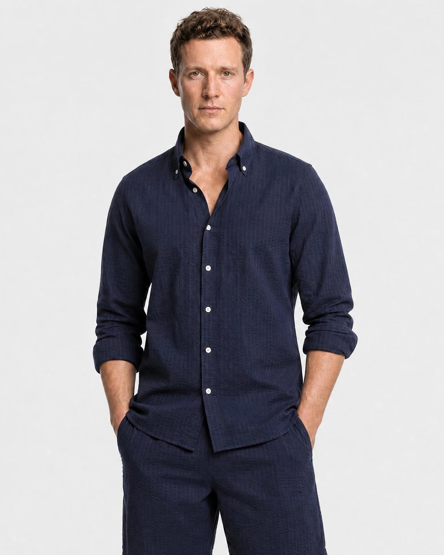 Navy Seersucker Hemd Herren Oberkörper, Button-Down-Kragen offen, Ärmel hochgekrempelt, zu navy Seersucker-Shorts