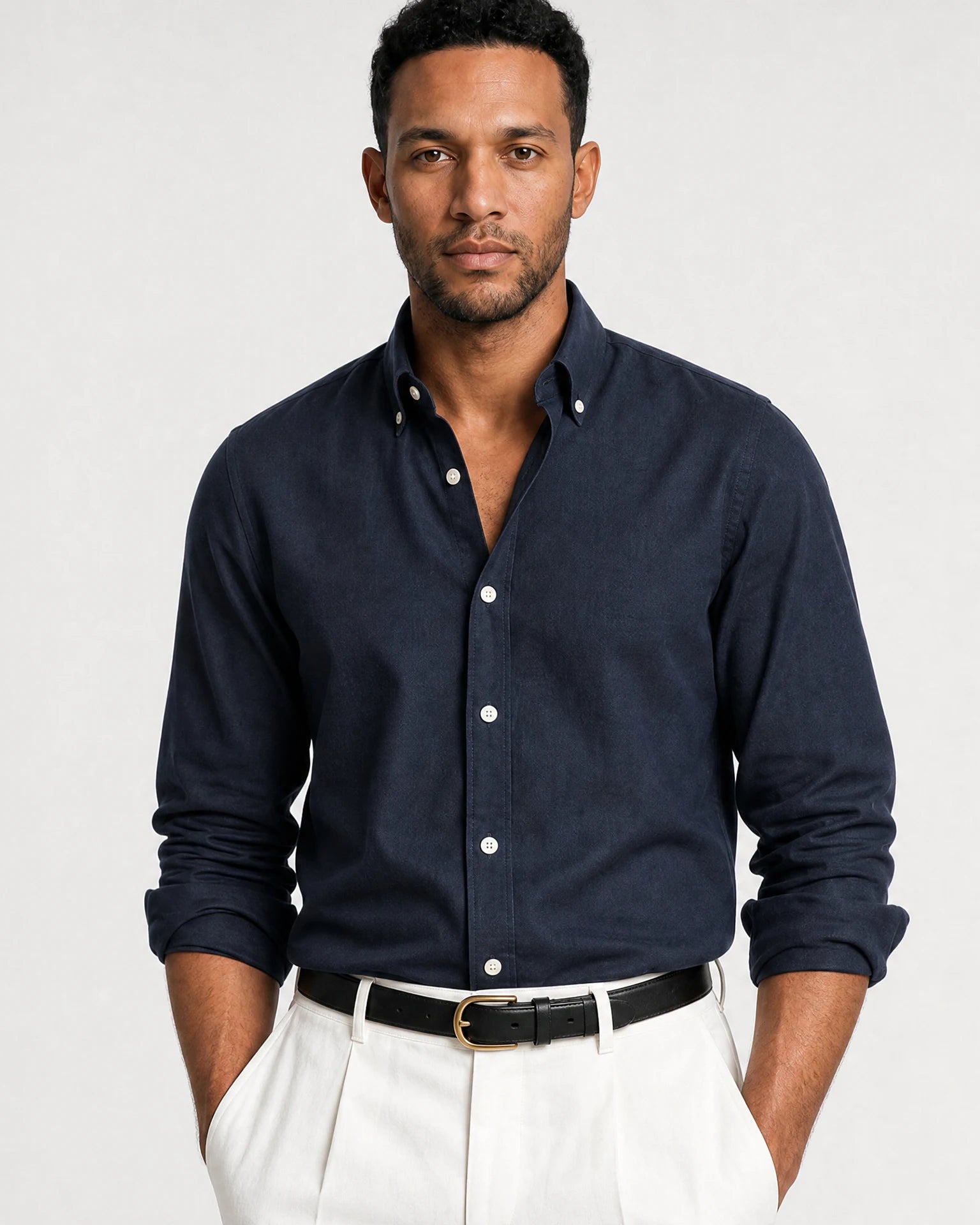 Dunkelblaues Navy Oxford-Hemd am Model mit offenem Button-Down-Kragen, weißen Knöpfen und weißer Hose.