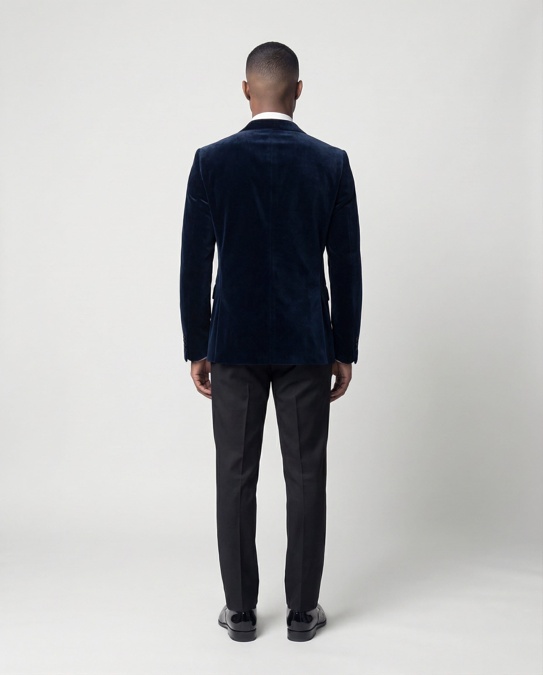 Mann im dunkelblauen Samtsakko mit schwarzer Hose von hinten gezeigt