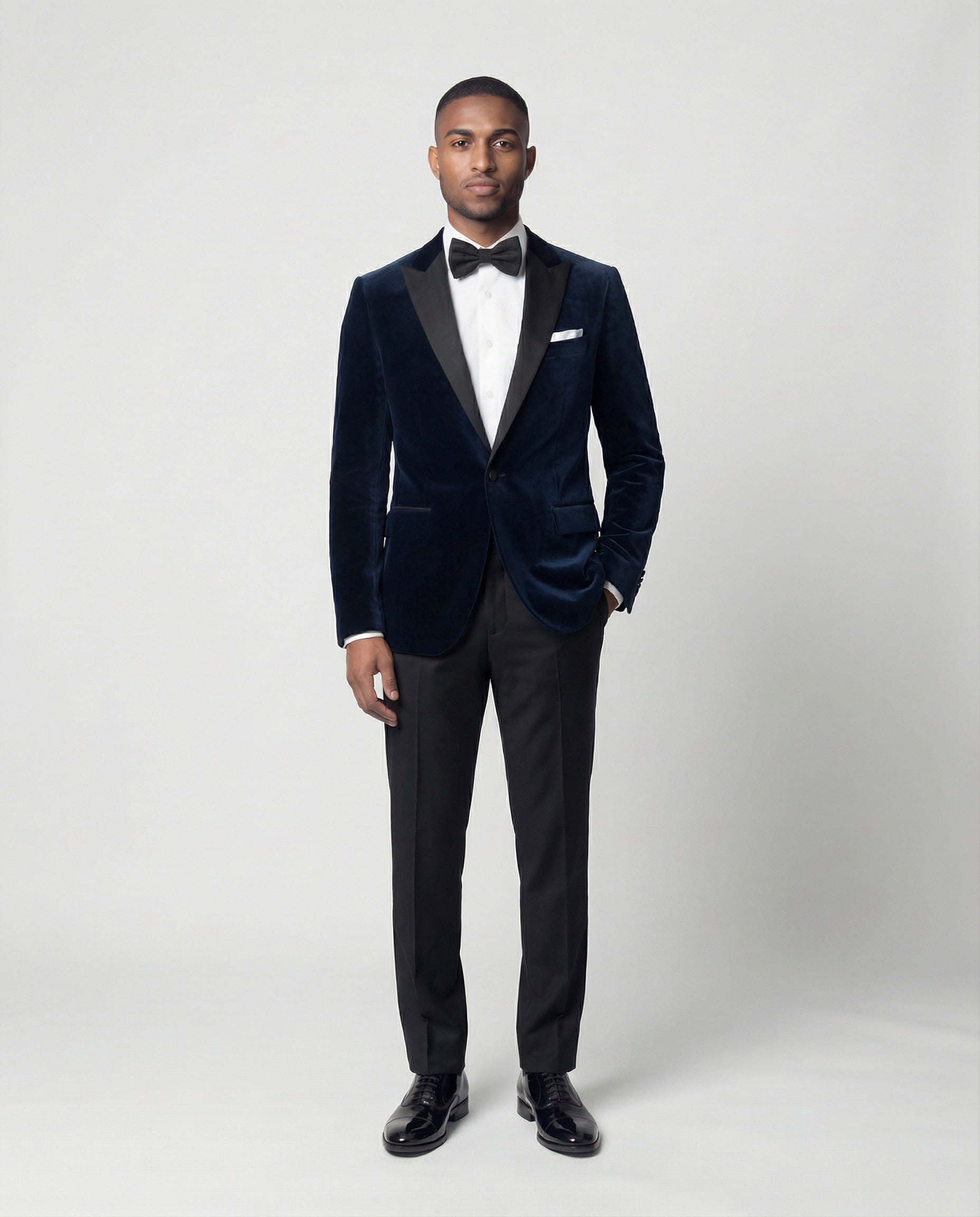 Mann im dunkelblauen Samtsakko mit schwarzer Hose von vorne mit Hand in der Tasche