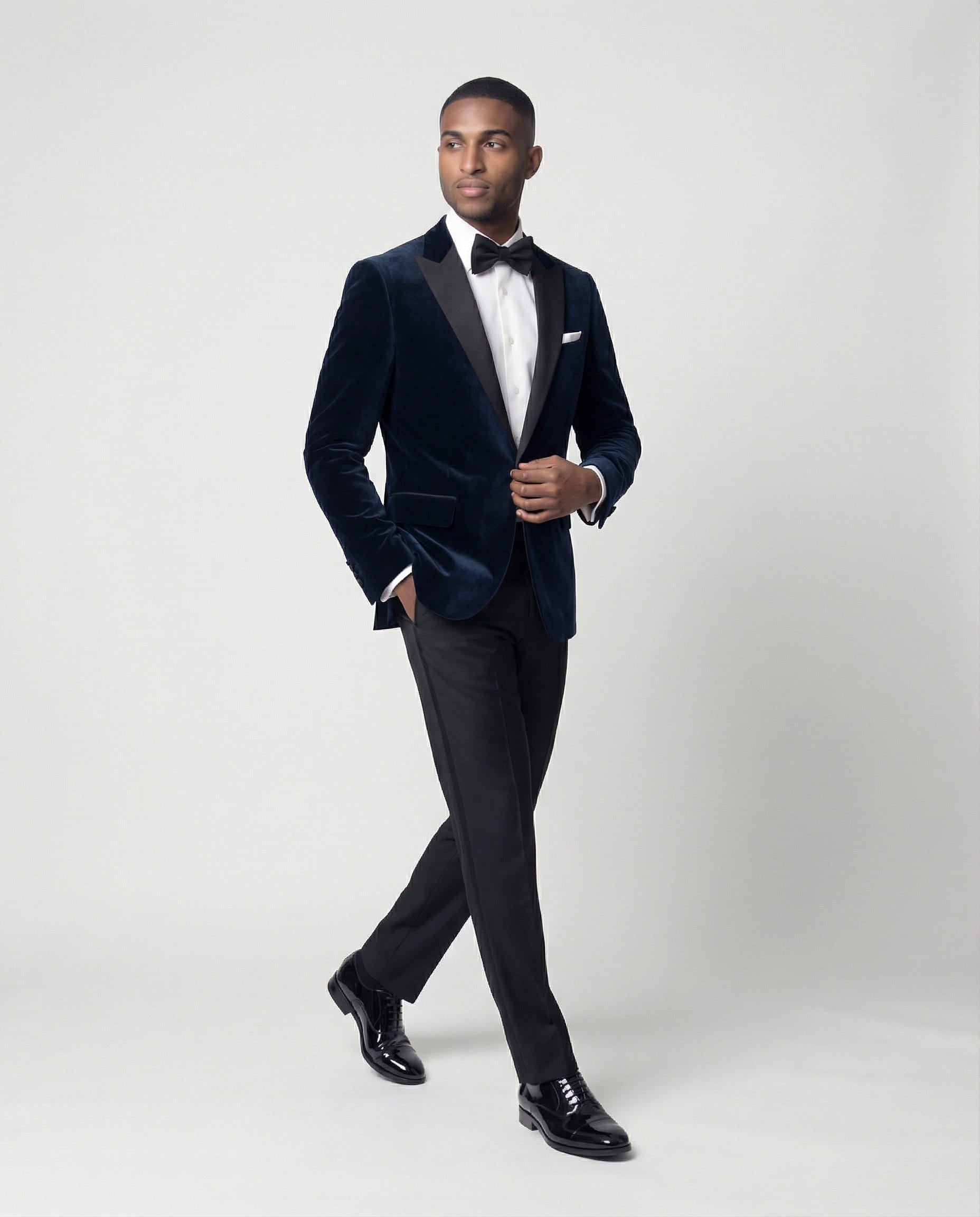 Mann im dunkelblauen Samtsakko mit schwarzer Hose in Bewegung mit Hand in der Tasche seitlich abgebildet