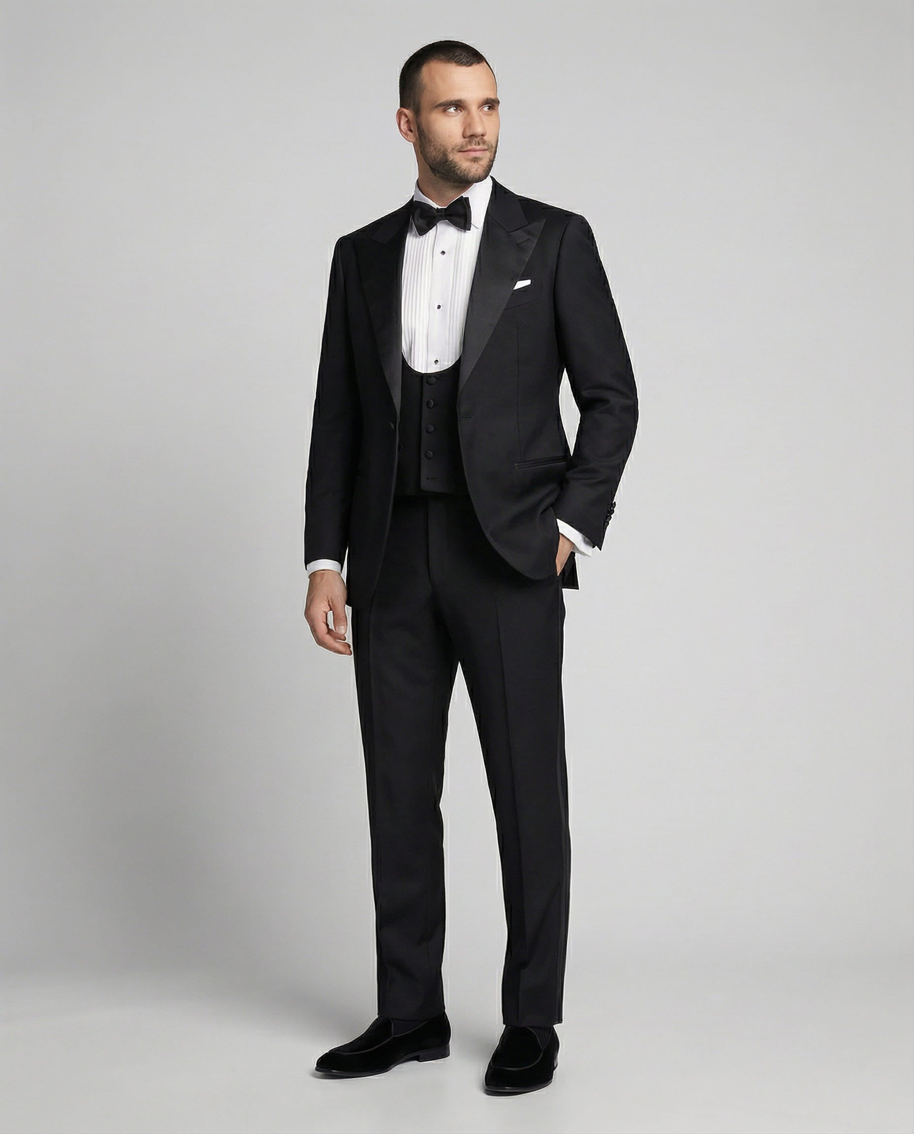 Mann im schwarzen Smoking mit Weste und Hand in der Tasche von vorne abgebildet