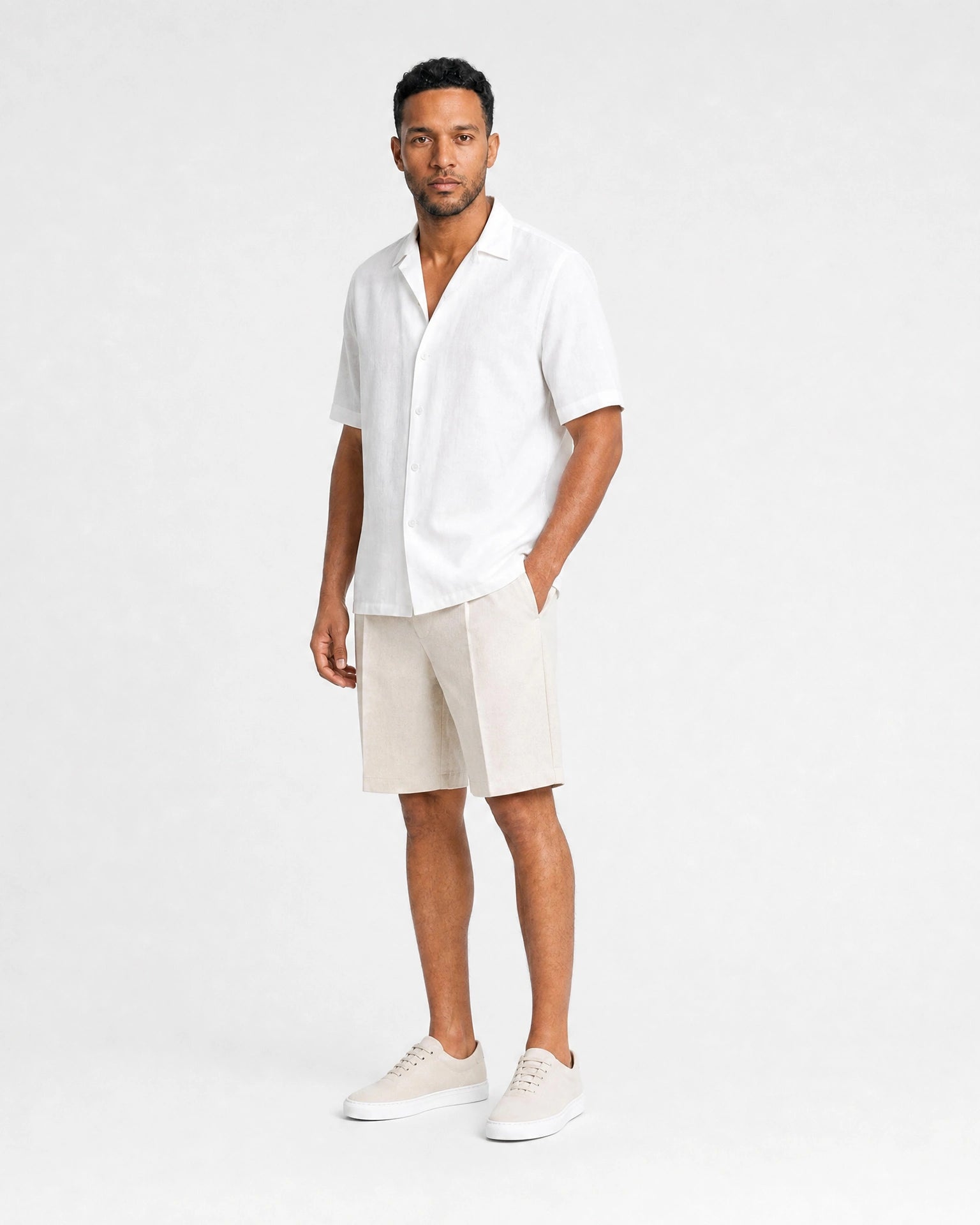 Weißes Leinen Kurzarmhemd Herren Dreiviertelansicht, Hand in Tasche, beige Leinenshorts und beige Sneaker