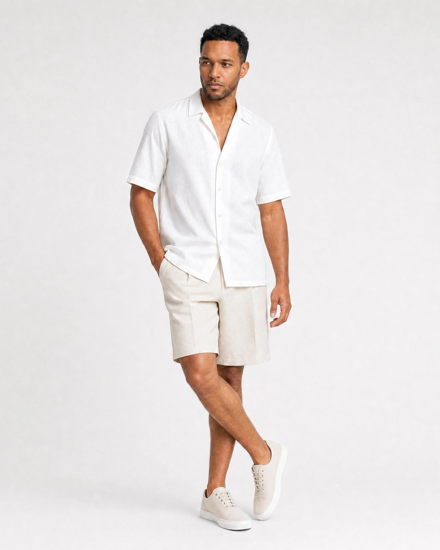 Weißes Leinen Kurzarmhemd Herren Ganzkörper mit seitlichem Blick, beige Leinenshorts, Sneaker, entspannte Sommerposes