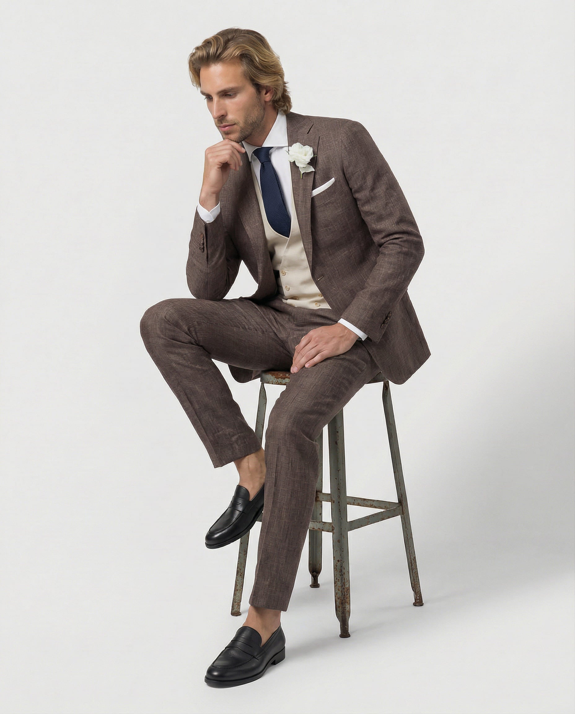 Mann im braunen Anzug mit cremefarbener Weste sitzend auf dem Hocker