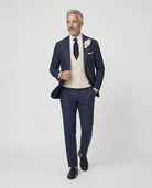 Mann im dunkelblauen Anzug mit beiger Weste Hand am Sakko
