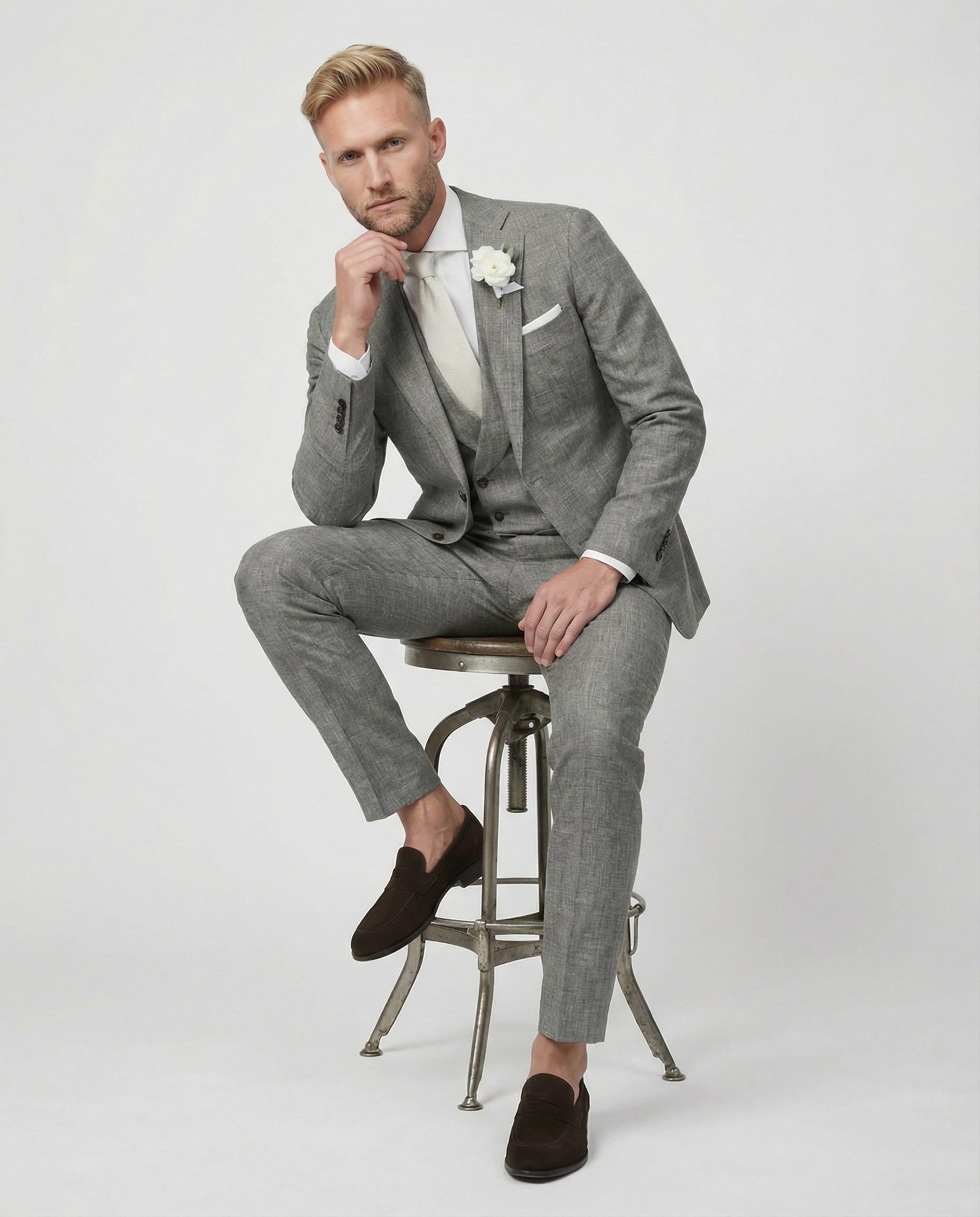 Mann im grauen Anzug mit Weste auf dem Hocker sitzend