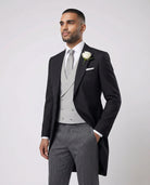 Mann im anthraziten Cutaway mit hellgrauer Weste und Stresemann Hose als Nahaufnahme mit Hand in der Tasche