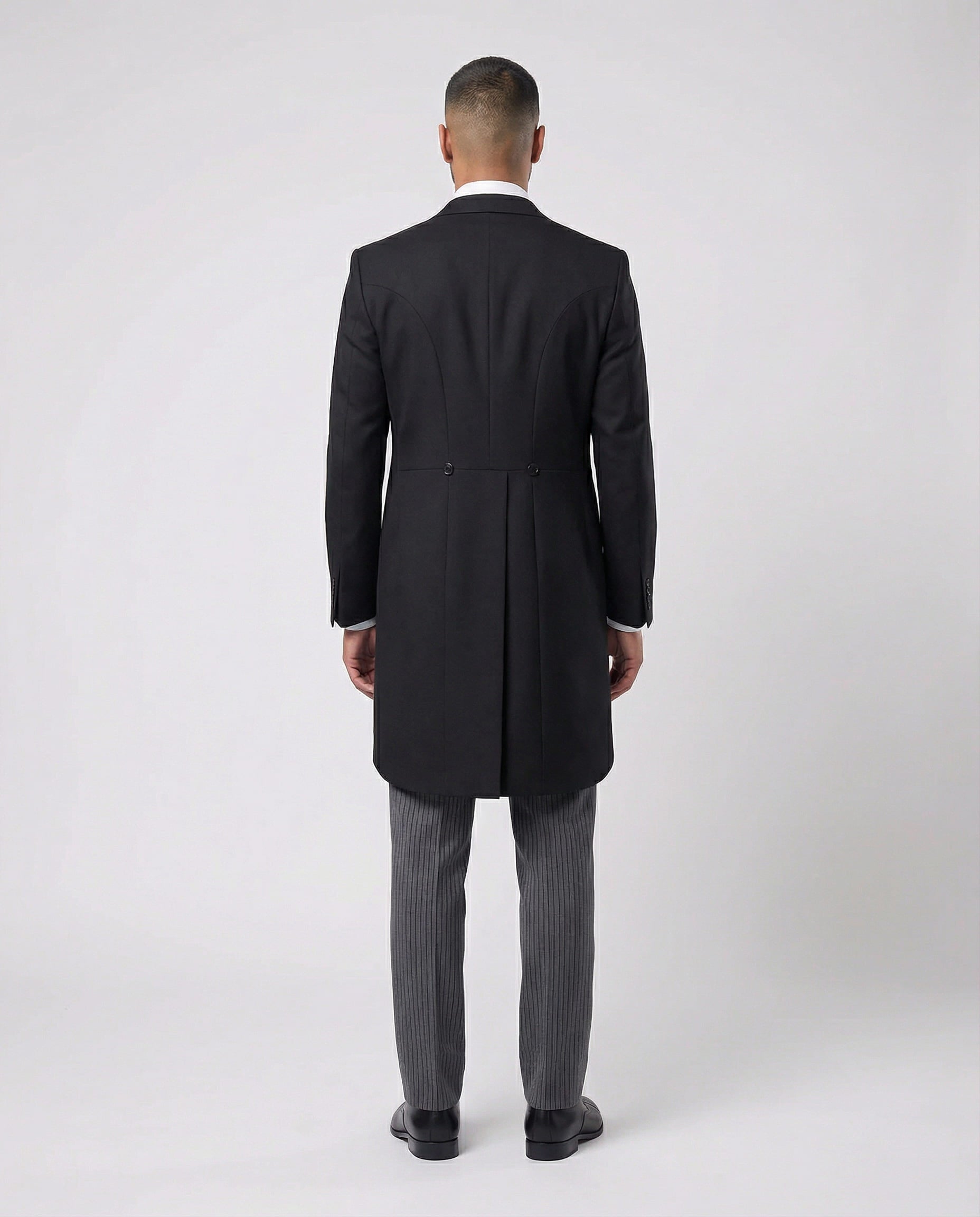 Mann im anthraziten Cutaway mit hellgrauer Weste und Stresemann Hose von hinten gezeigt