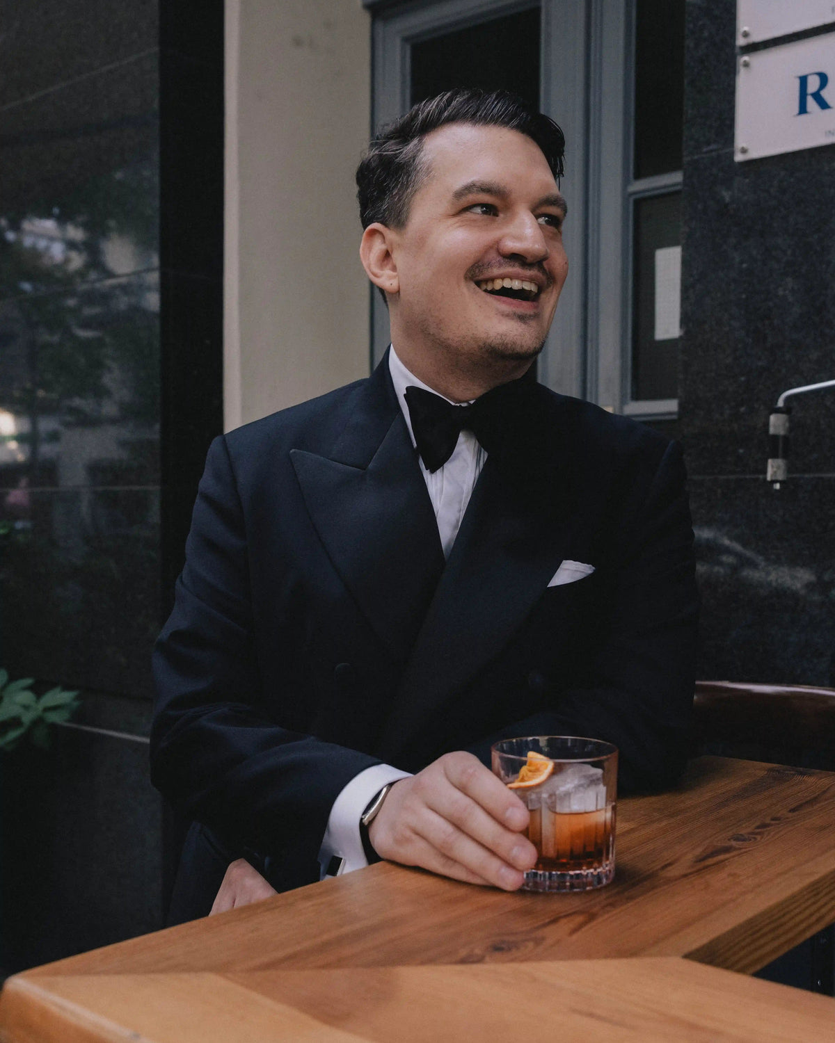 Elegante Black-Tie-Inspiration für Herren mit schwarzem Smoking in einer Bar in warmer Abendatmosphäre.