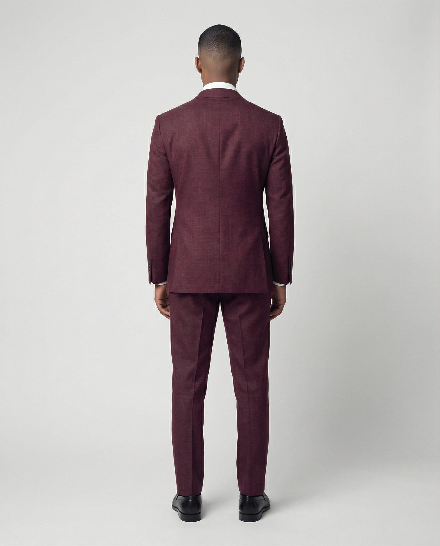 Mann im bordeauxroten Anzug von hinten fotografiert