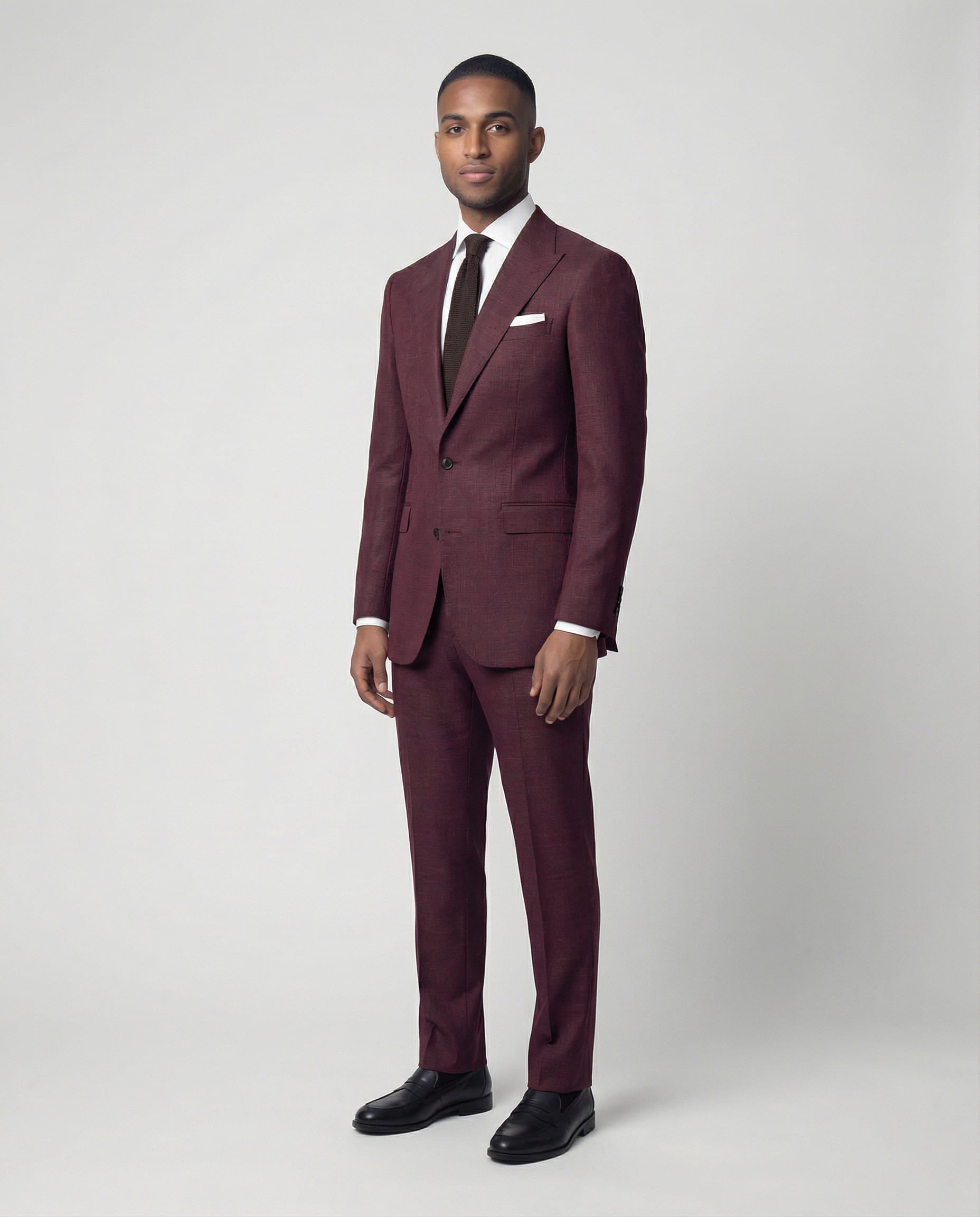 Mann im bordeauxroten Anzug seitlich fotografiert