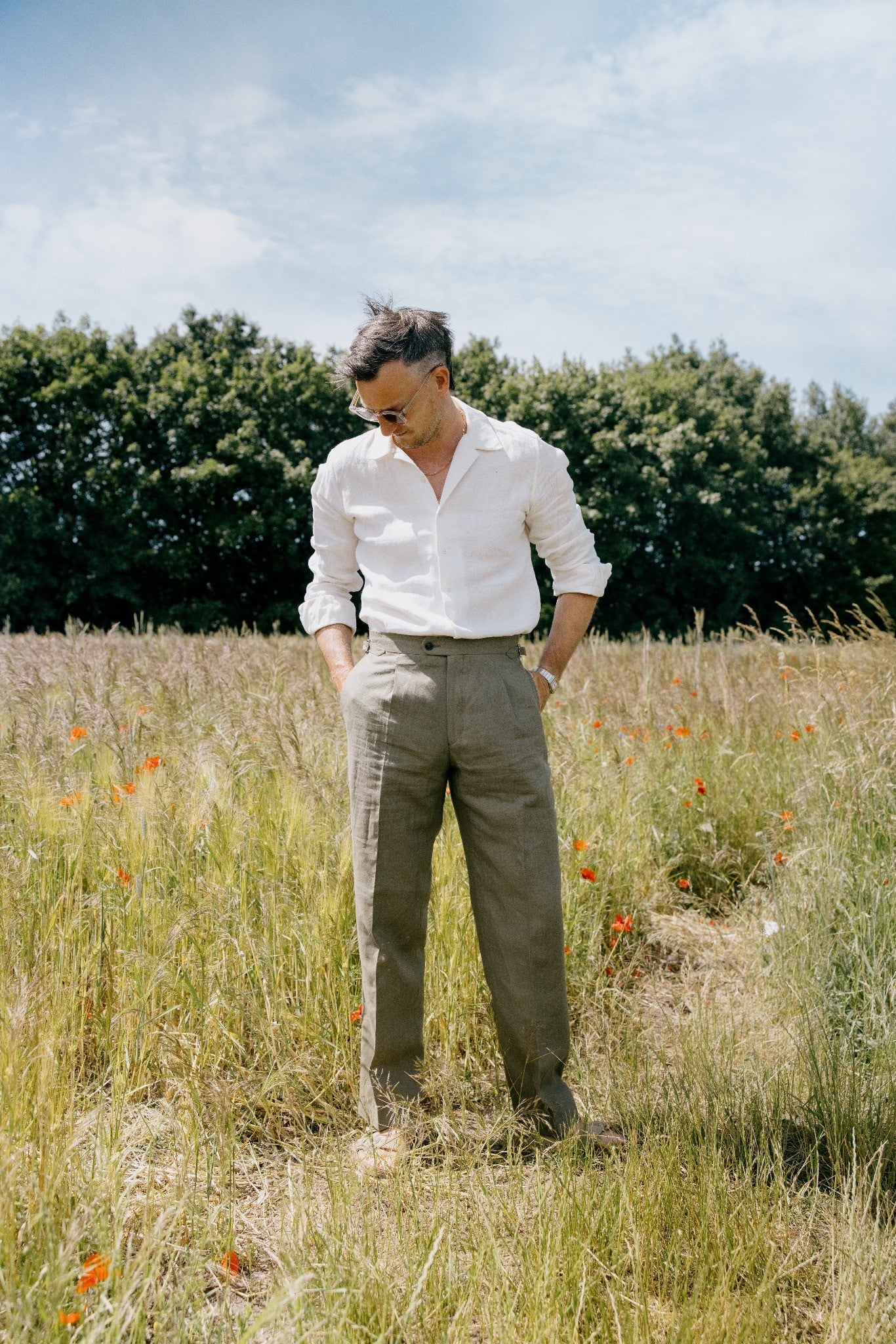 Sommerlicher Casual-Tailoring-Look mit weißem Leinenhemd und grüner Leinenhose in der Wiese