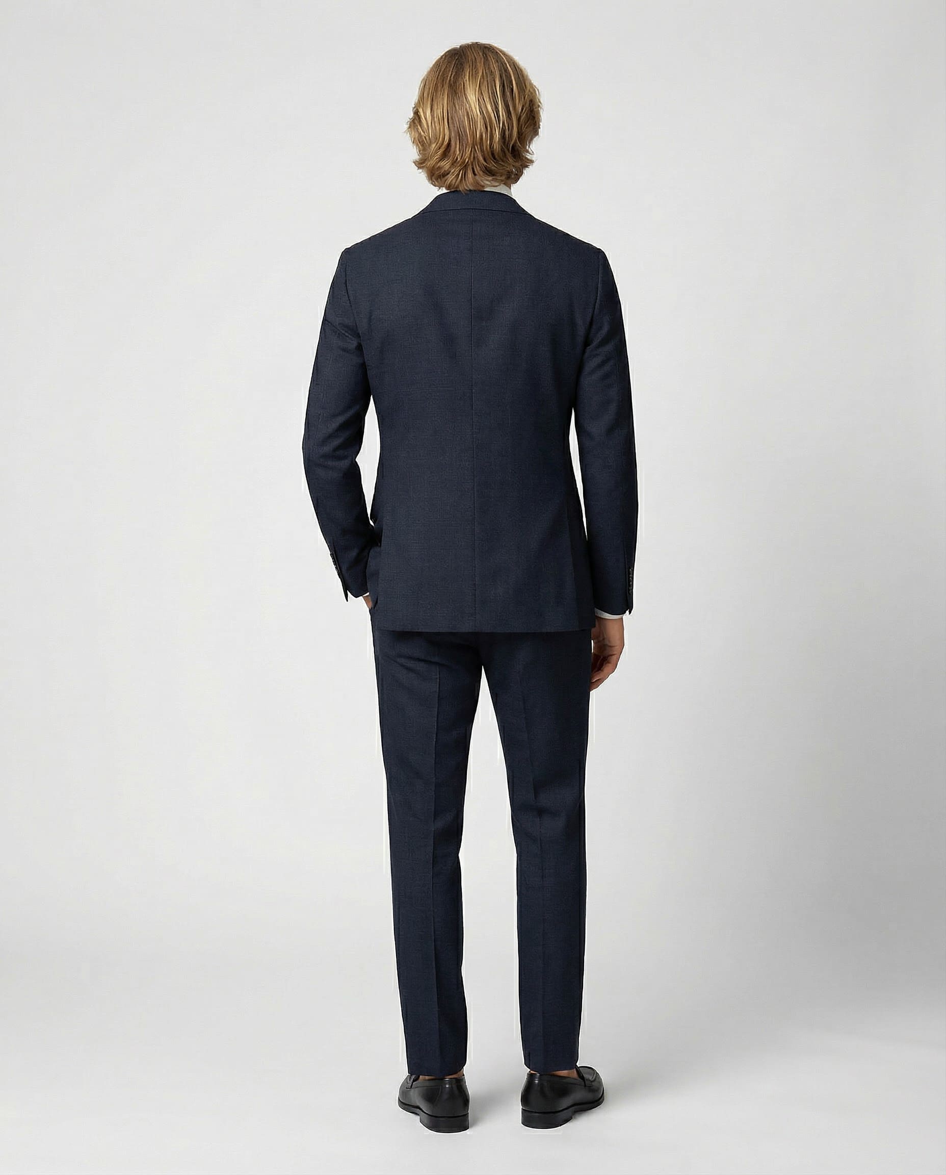 Mann im dunkelblauen Anzug aus leicht strukturierter Schurwolle mit offener Webung von hinten abgebildet