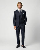 Mann im dunkelblauen Anzug aus leicht strukturierter Schurwolle mit offener Webung mit Weste und Hand in der Tasche
