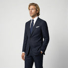 Mann im dunkelblauen Anzug aus leicht strukturierter Schurwolle mit offener Webung Nahaufnahme mit Hand in der Tasche