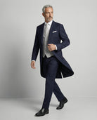 Mann im dunkelblauen Cutaway mit hellgrauer Weste in Bewegung seitlich gezeigt