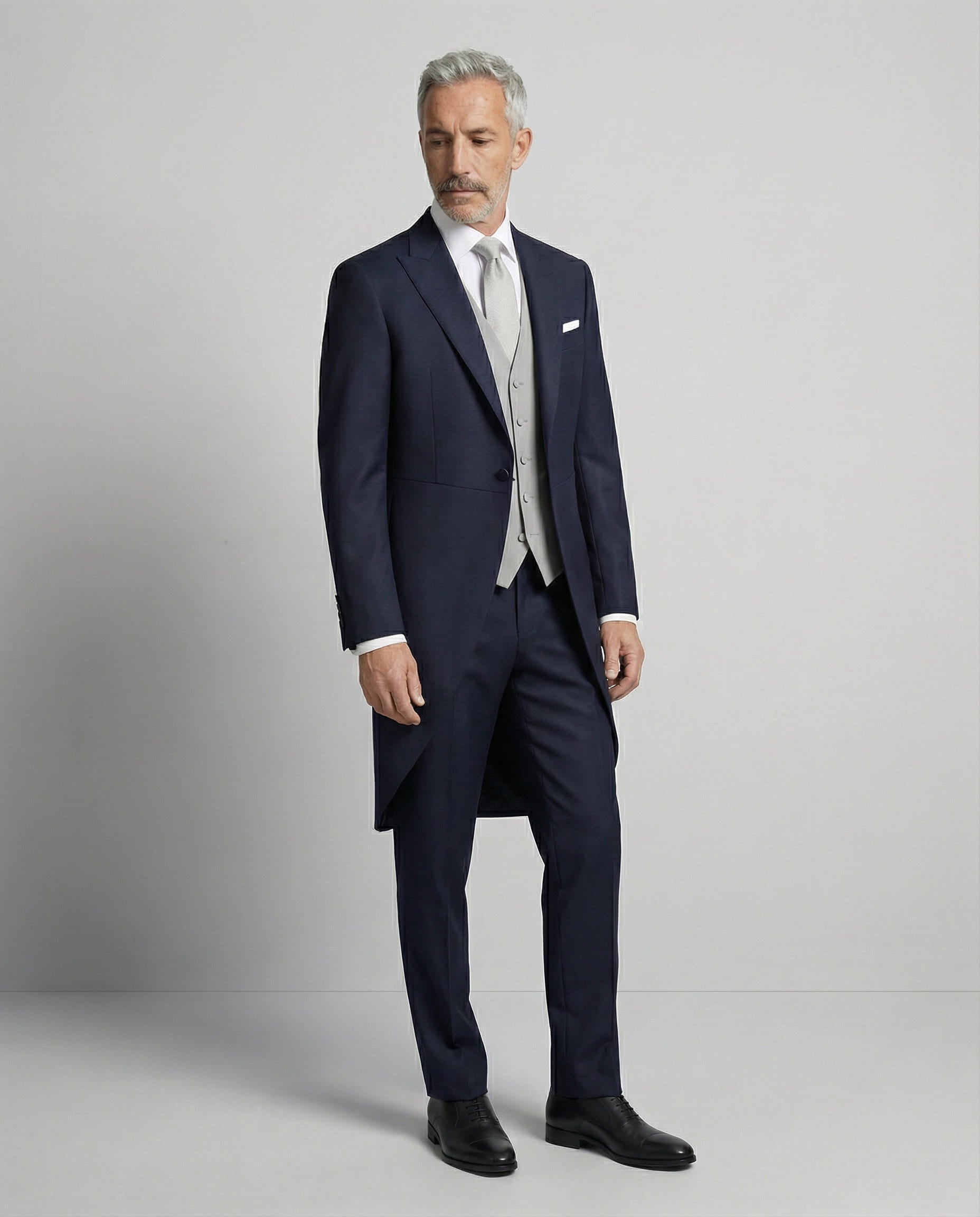 Mann im dunkelblauen Cutaway mit hellgrauer Weste seitlich gezeigt mit offenem Sakko