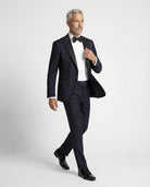 Mann im dunkelblauen Smoking in Bewegung seitlich abgebildet mit offenem Sakko