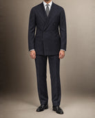 Mann im dunkelblauen Zweireiher-Anzug aus Vitale-Barberis-Canonico-Flanell mit weißem Hemd, grauer Krawatte und schwarzen Quasten-Loafern, frontal