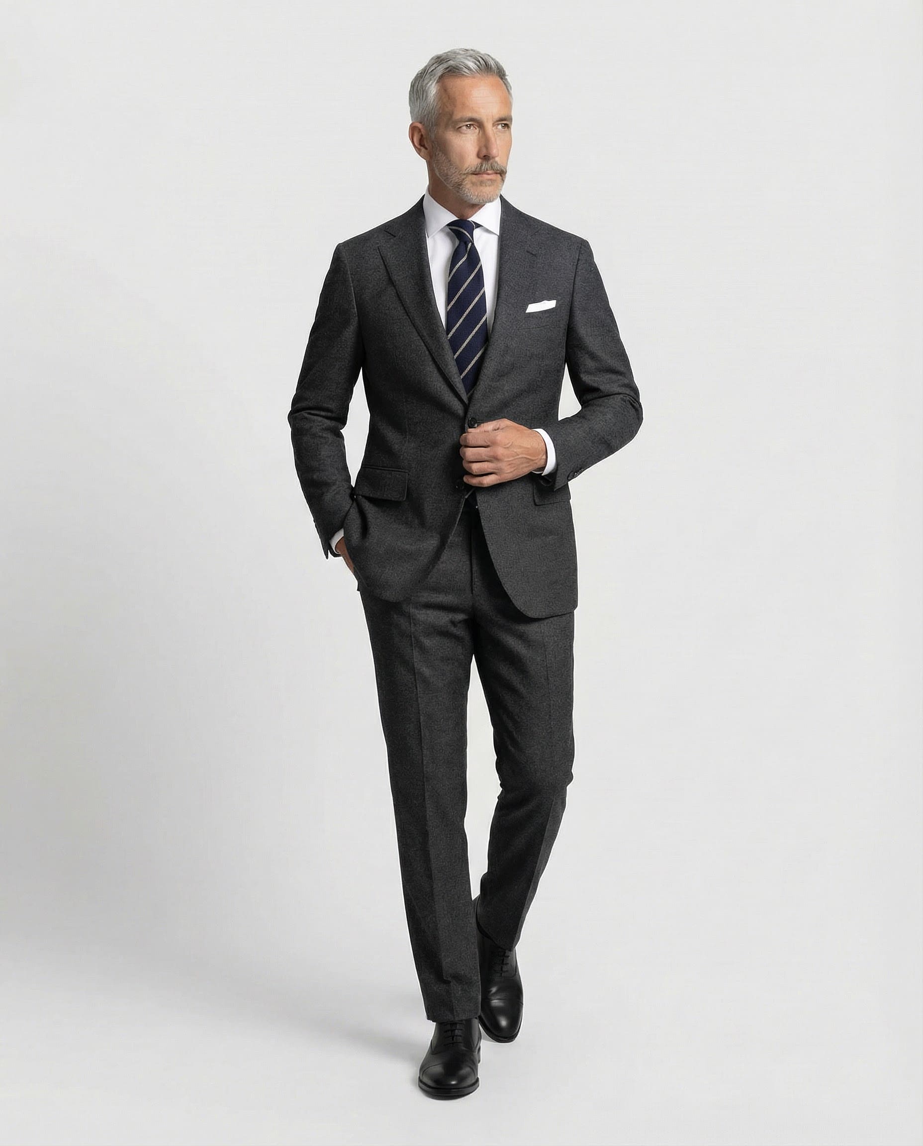 Mann im dunkelgrauen Anzug aus leicht strukturierter Schurwolle mit offener Webung in Bewegung von vorne abgebildet