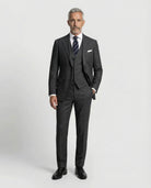 Mann im dunkelgrauen Anzug aus leicht strukturierter Schurwolle mit offener Webung mit Weste und Hand in der Tasche