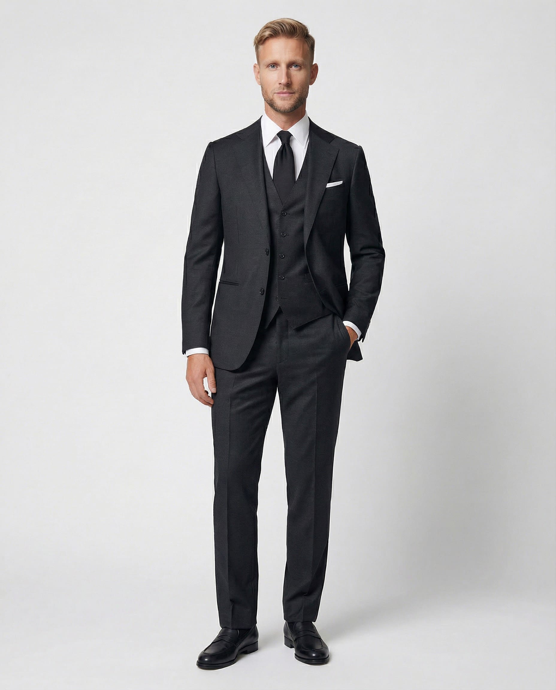 Mann im dunkelgrauen Anzug aus reiner Schurwolle mit Weste und Hand in der Tasche von vorne