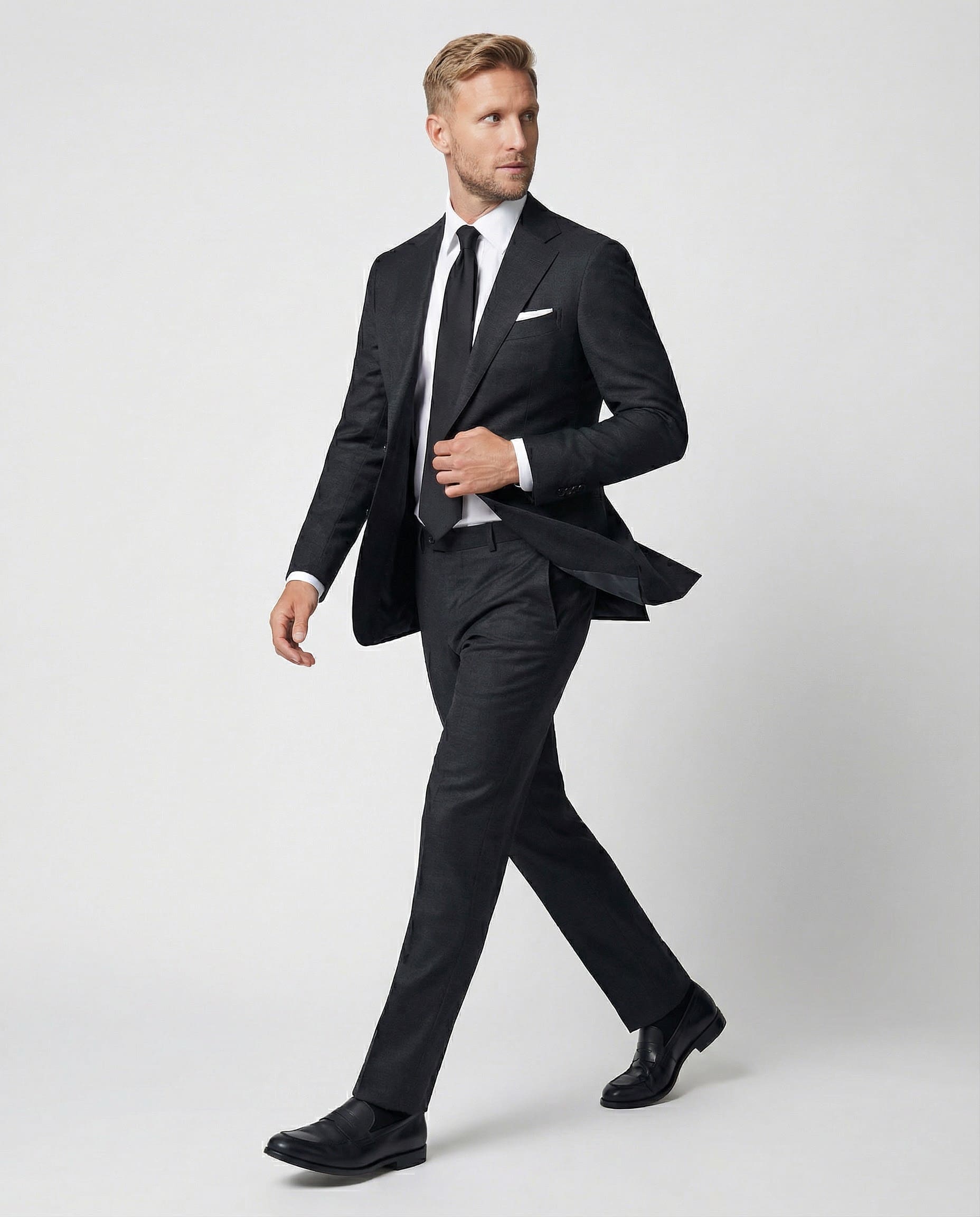 Mann im dunkelgrauen Anzug aus reiner Schurwolle in Bewegung seitlich abgebildet