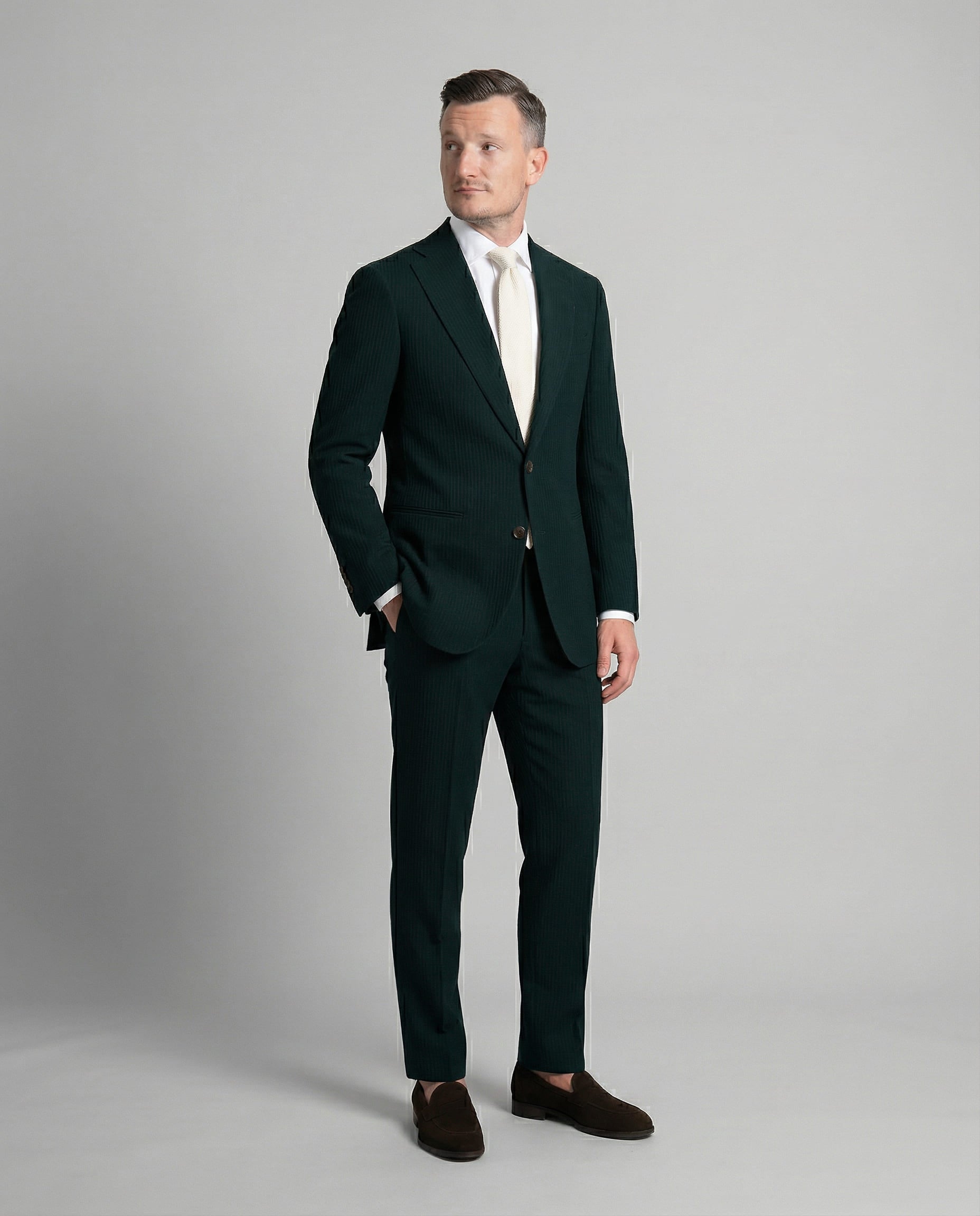 Mann im dunkelgrünen Seersucker Anzug mit Hand in der Tasche seitlich abgebildet