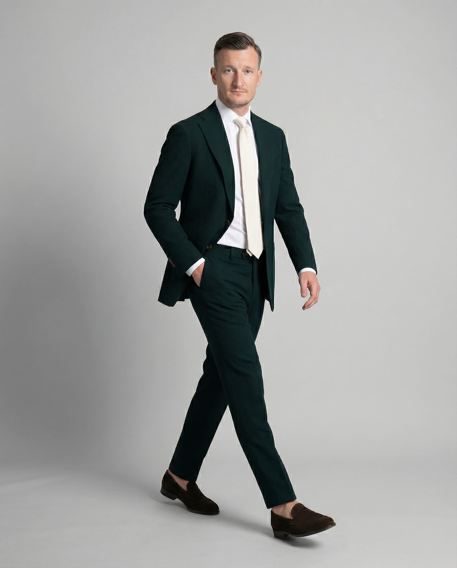 Mann im dunkelgrünem Seersucker Anzug in Bewegung mit Hand in der Tasche