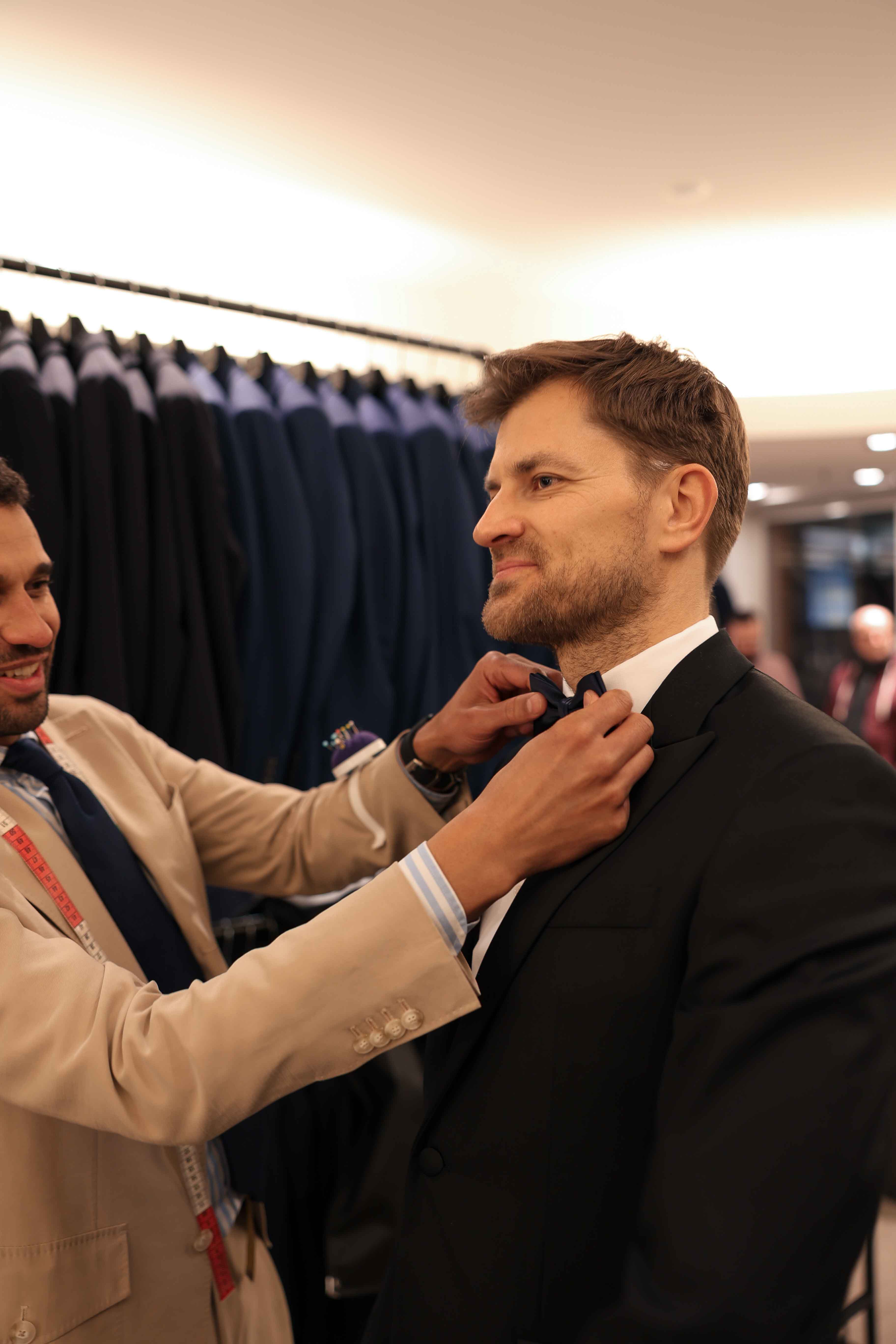 Anprobe des Hochzeitsanzuges bei dem die Schleife gerichtet wird