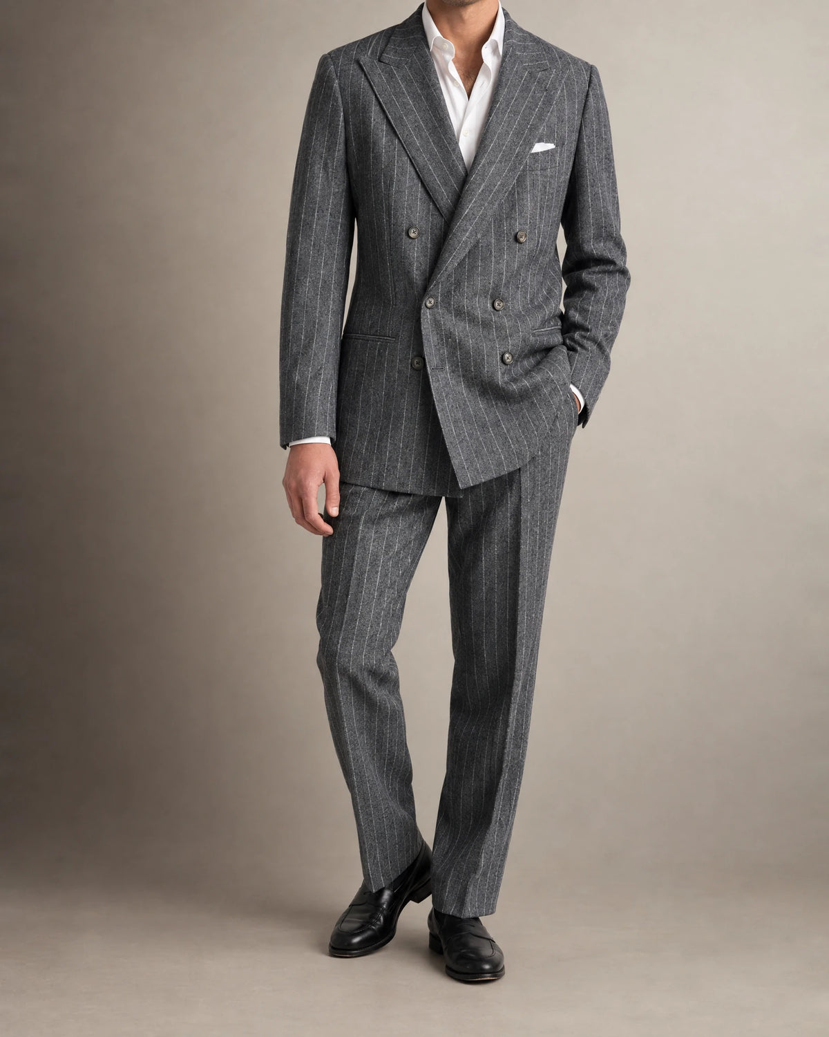 Mann im zweireihigen Chalk-Stripe-Anzug aus grauem Flanell mit Hand in der Hosentasche, Ganzkörperansicht mit weißem Einstecktuch
