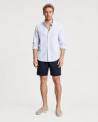 Hellblau-weiß gestreiftes Seersucker Hemd Herren Ganzkörper frontal, kombiniert mit navy Seersucker-Shorts und beigen Suede-Loafern