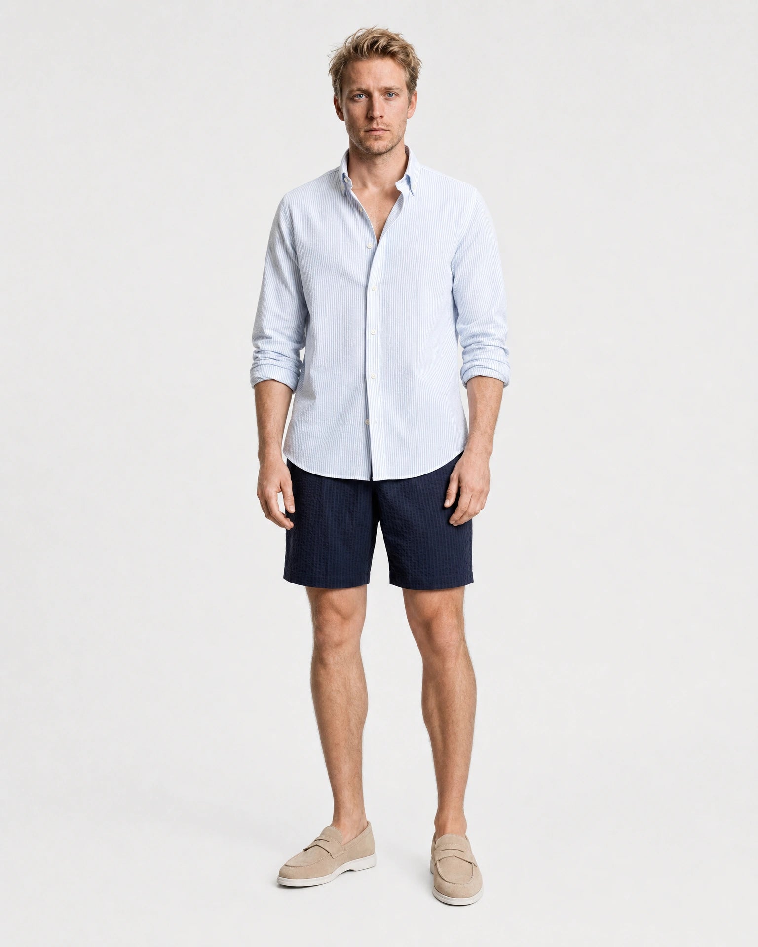 Hellblau-weiß gestreiftes Seersucker Hemd Herren Ganzkörper frontal, kombiniert mit navy Seersucker-Shorts und beigen Suede-Loafern