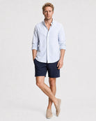 Hellblau-weiß gestreiftes Seersucker Hemd Herren lässige Pose, Hand in Tasche, navy Shorts und beige Loafer