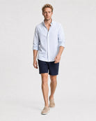Hellblau-weiß gestreiftes Seersucker Hemd Herren in Laufpose, navy Seersucker-Shorts und beige Suede-Loafer
