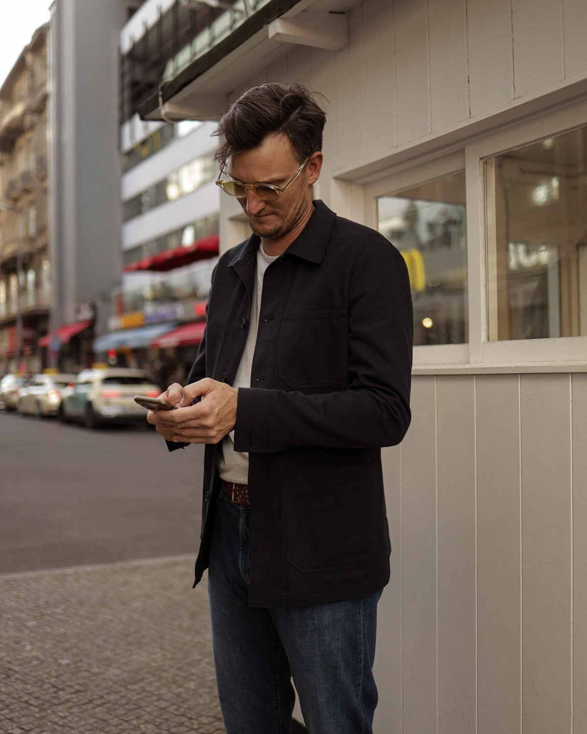 Viktor steht im casual Outfit mit Handy in der Hand