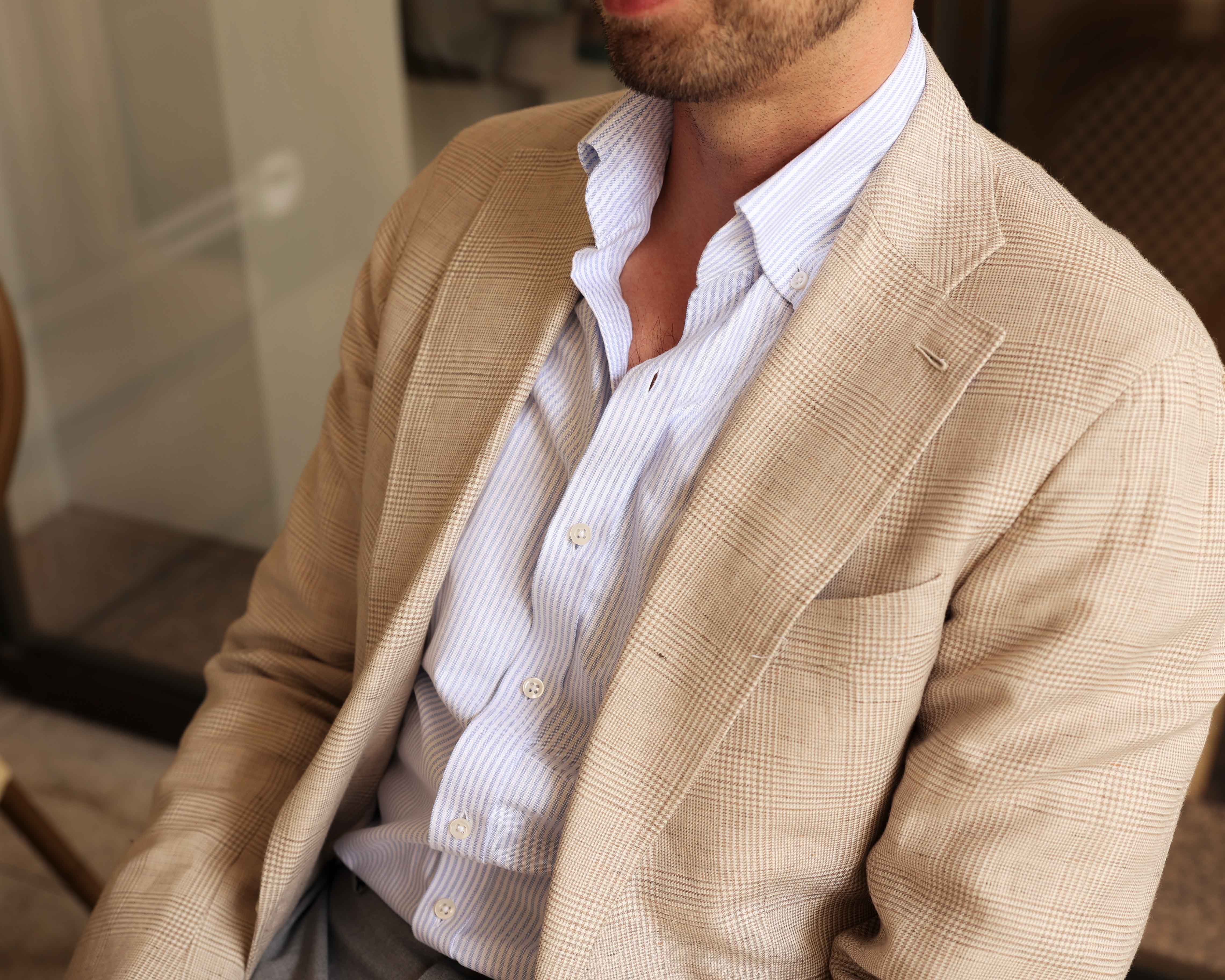 Simon im casual Sakko sitzen mit blau weiß gestreiftem Oxford Hemd