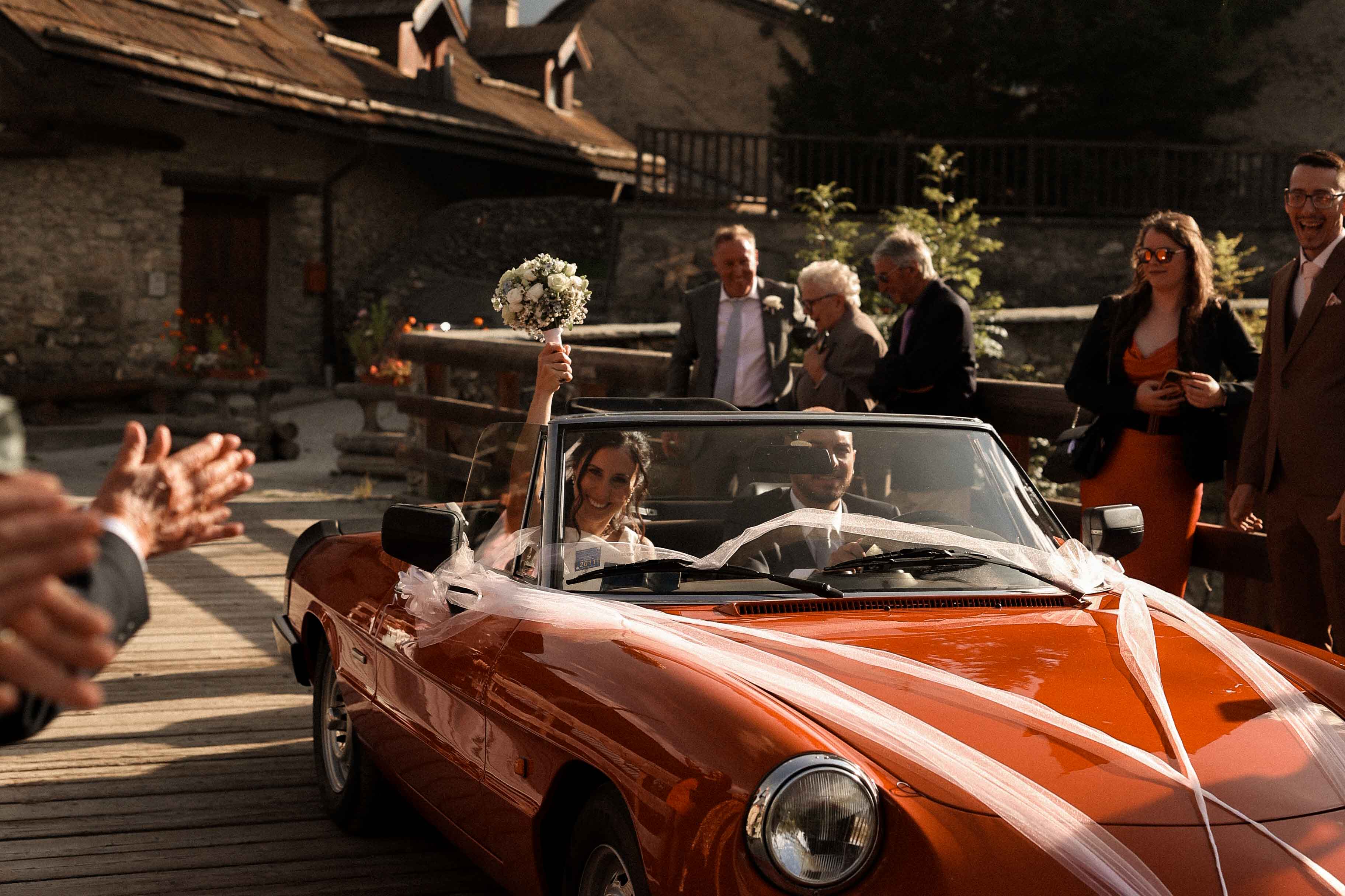 Brautpaar sitzt in rotem Auto