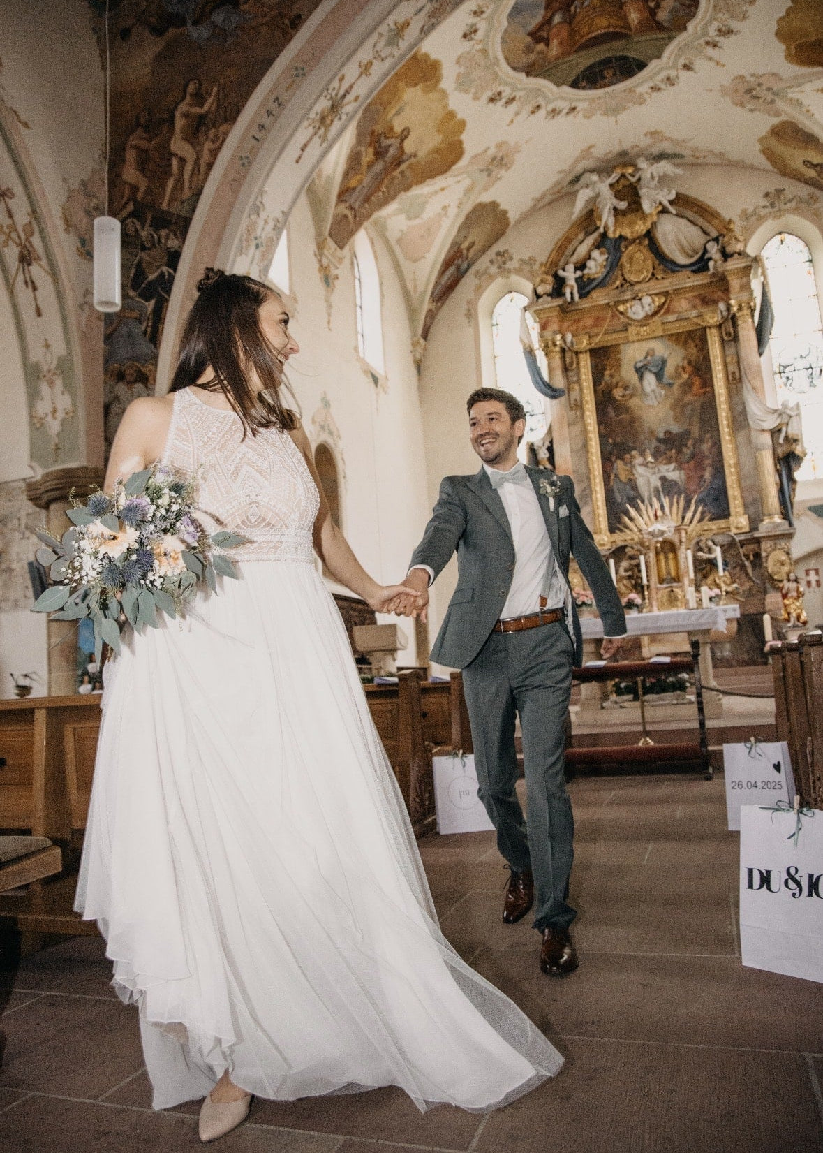 Ein Brautpaar verlässt händehaltend die Kirche