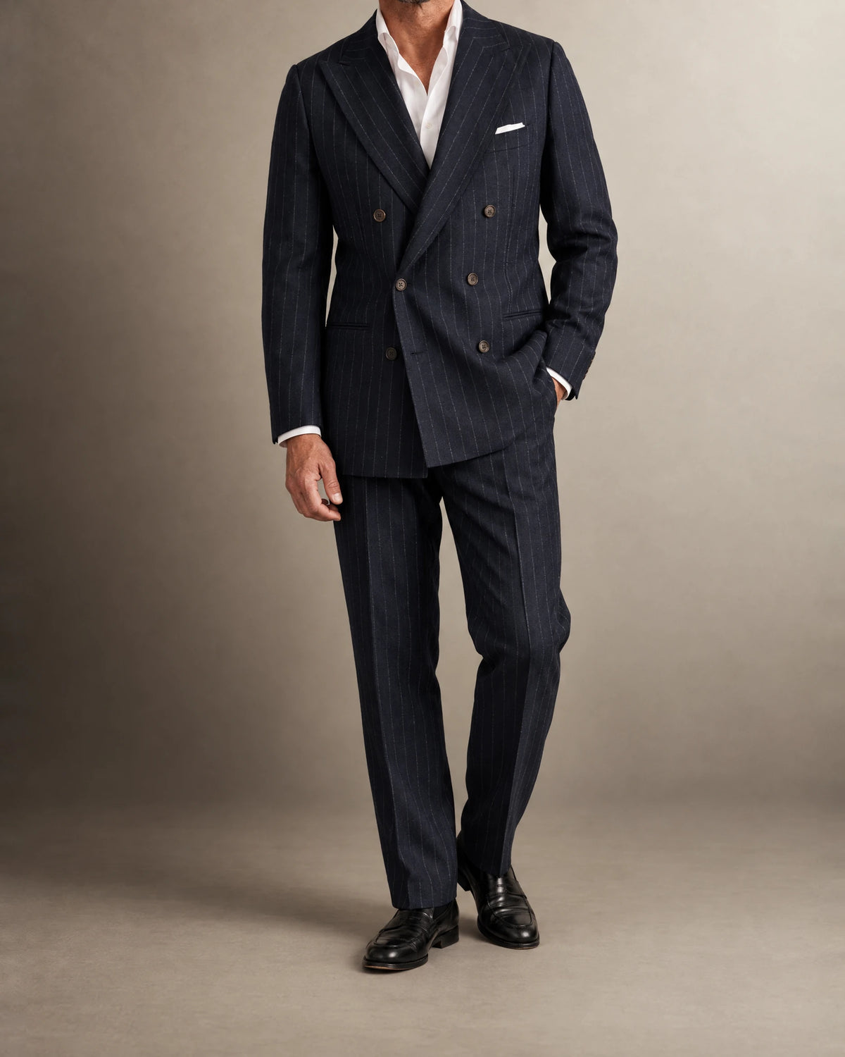 Mann im zweireihigen Chalk-Stripe-Anzug aus navy Flanell mit Hand in der Hosentasche, Ganzkörperansicht mit weißem Einstecktuch