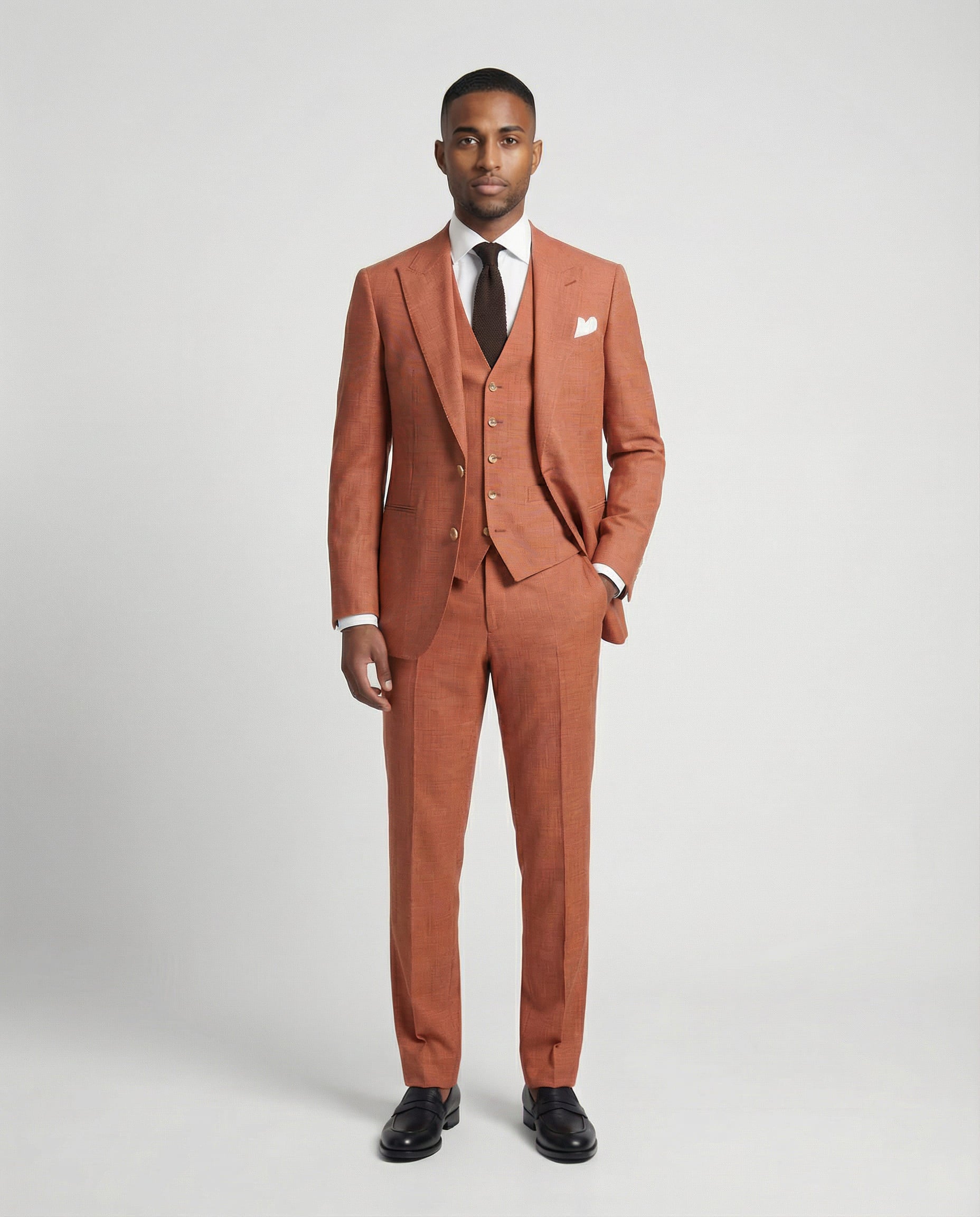 Mann im orangen Anzug mit Weste und Hand in der Tasche von vorne fotografiert