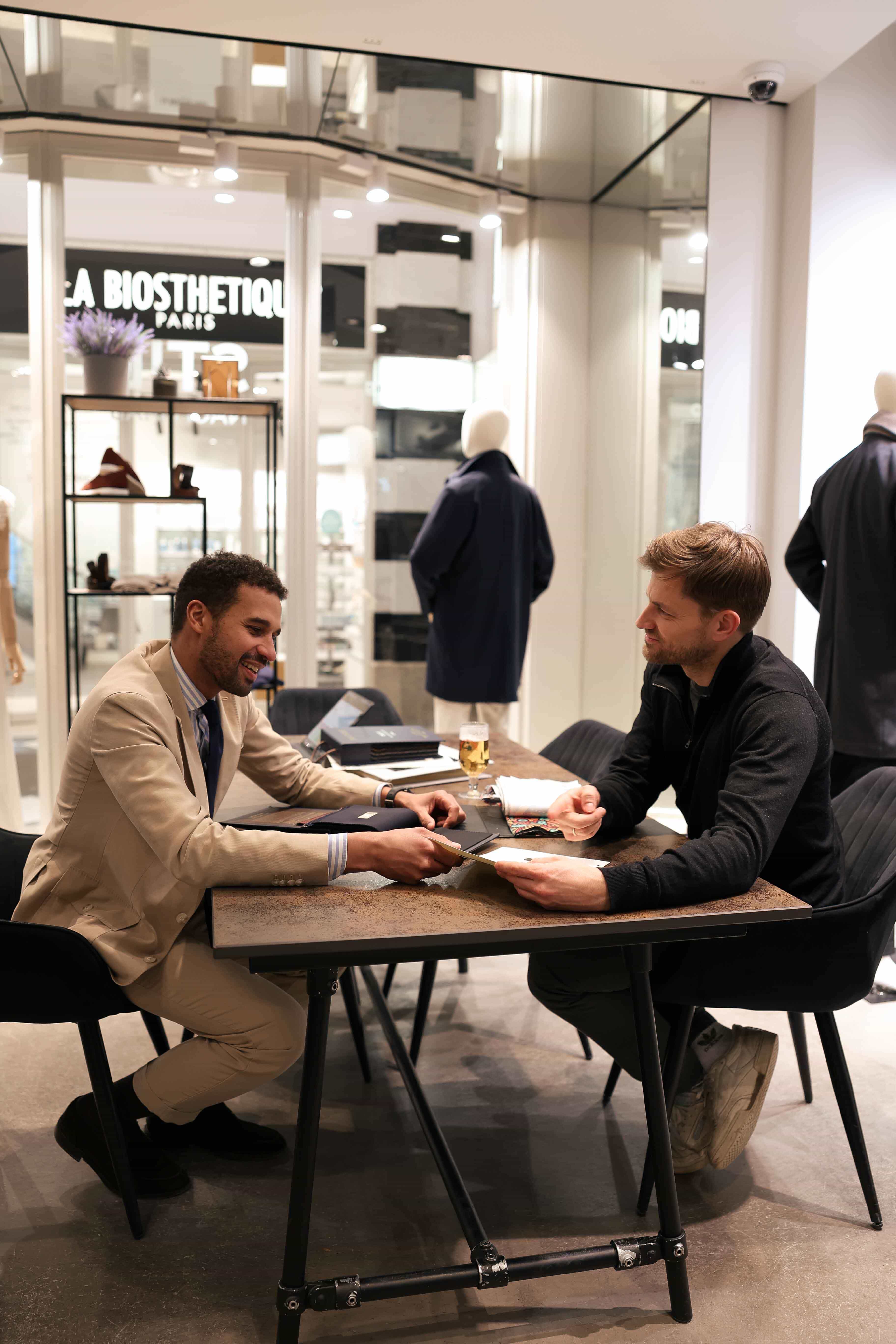 Rico erklärt dem Kunden die unterschiedliche Preise der Anzugstoffe