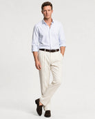 Herren Oxford-Hemd in Blau-Weiß gestreift kombiniert mit heller Hose, braunem Gürtel und Loafern.