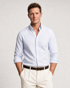 Halbkörperansicht eines Models mit blau-weiß gestreiftem Oxford-Hemd, heller Hose und braunem Gürtel.