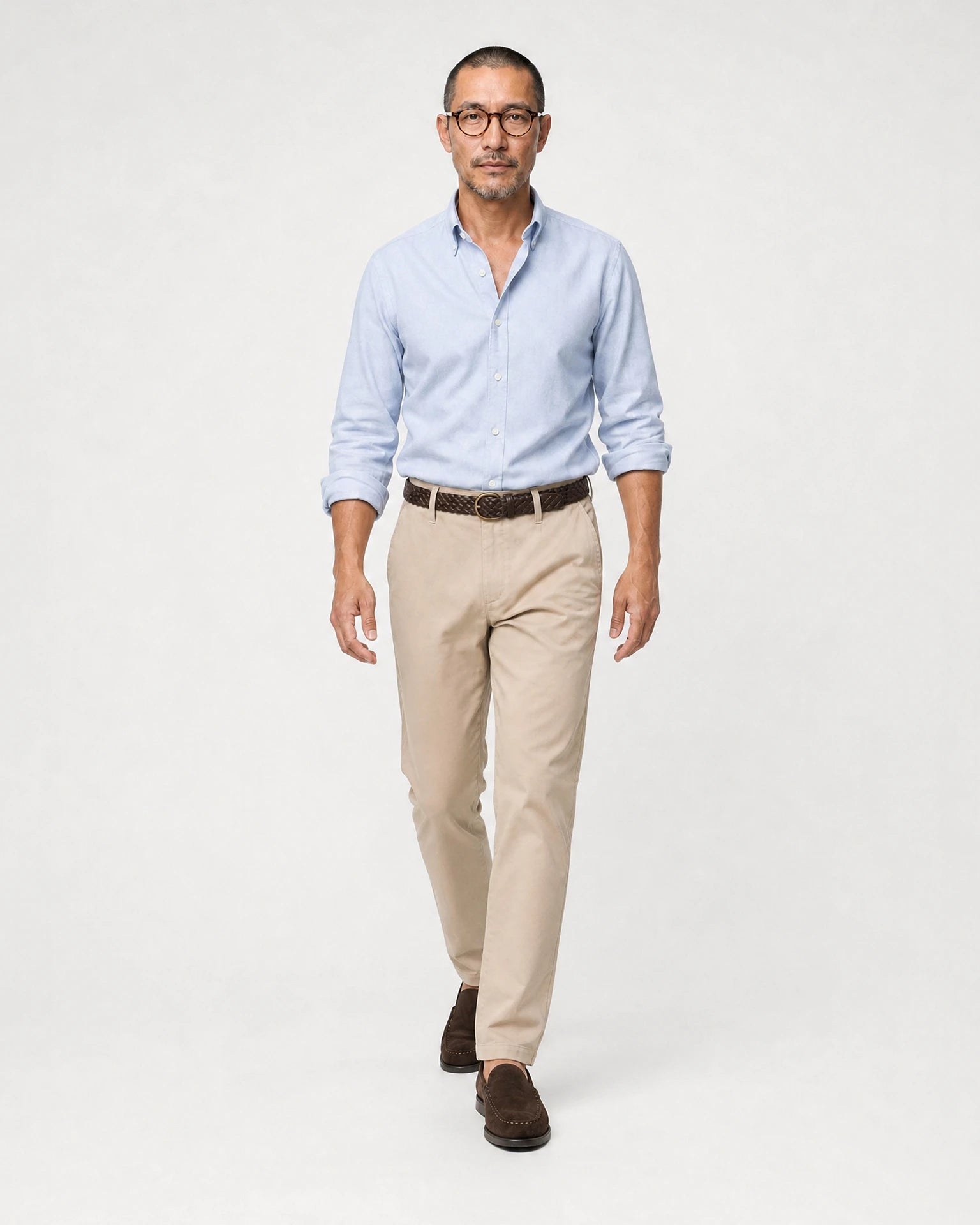 Herren Oxford-Hemd in Hellblau kombiniert mit beiger Hose, braunem Gürtel und braunen Loafern.
