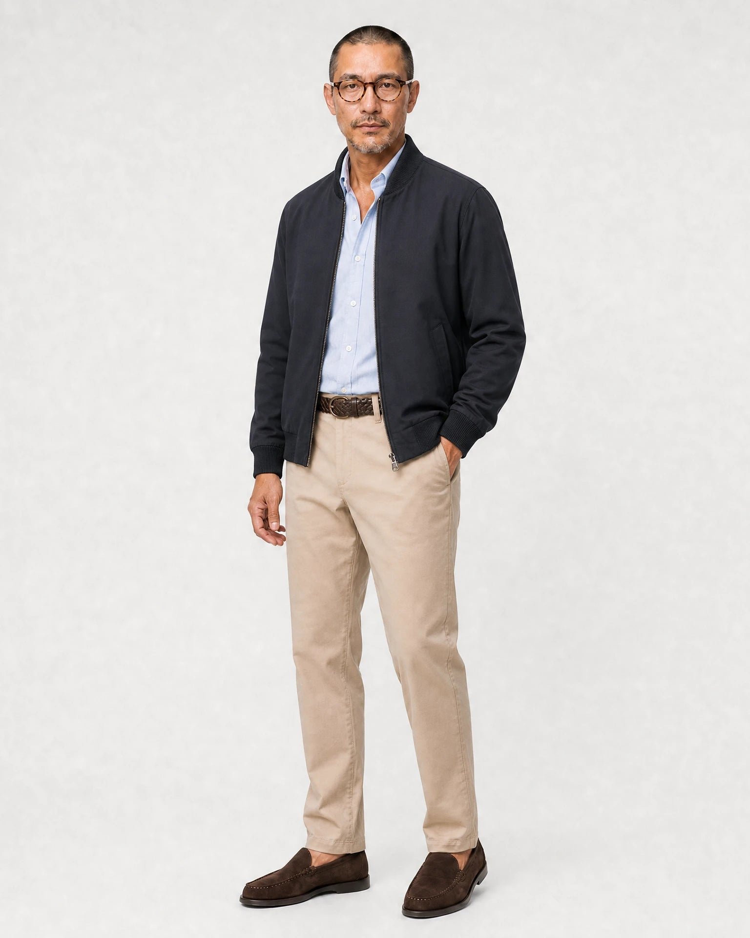 Hellblaues Oxford-Hemd kombiniert mit dunkler Jacke, beiger Hose und braunen Loafern.
