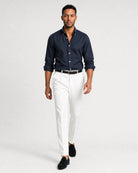 Herren Oxford-Hemd in Dunkelblau Navy kombiniert mit weißer Hose, schwarzem Gürtel und schwarzen Loafern.