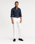Frontansicht eines Models mit dunkelblauem Navy Oxford-Hemd, weißer Hose und schwarzen Loafern.